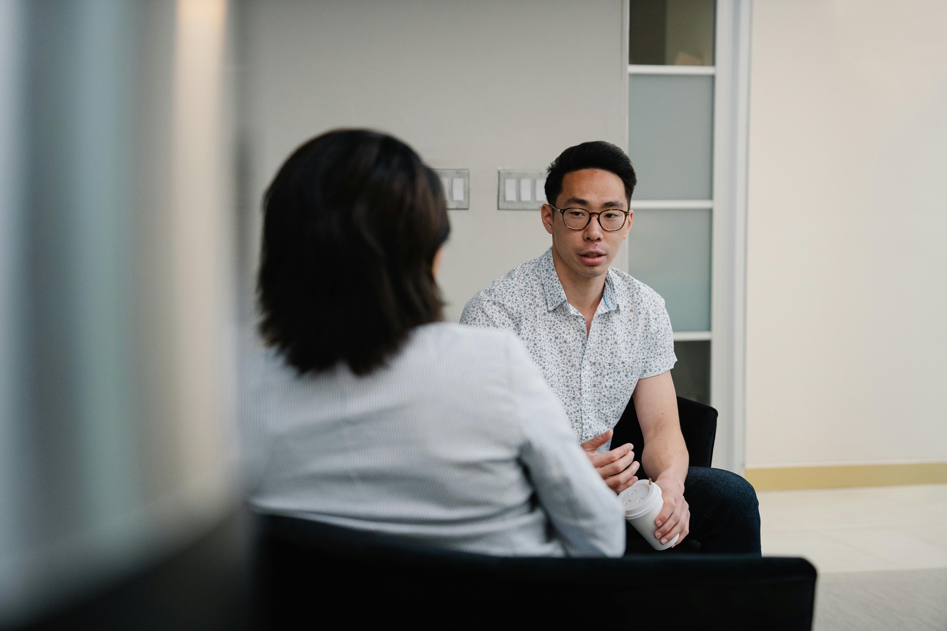 Two professionals in conversation across chairs in a modern office