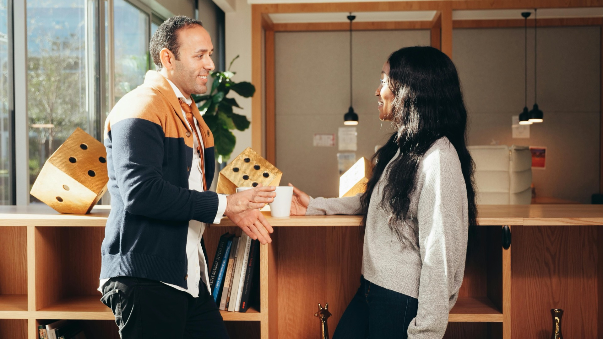 Two people talking warmly over coffee at a counter in a sunlit room
