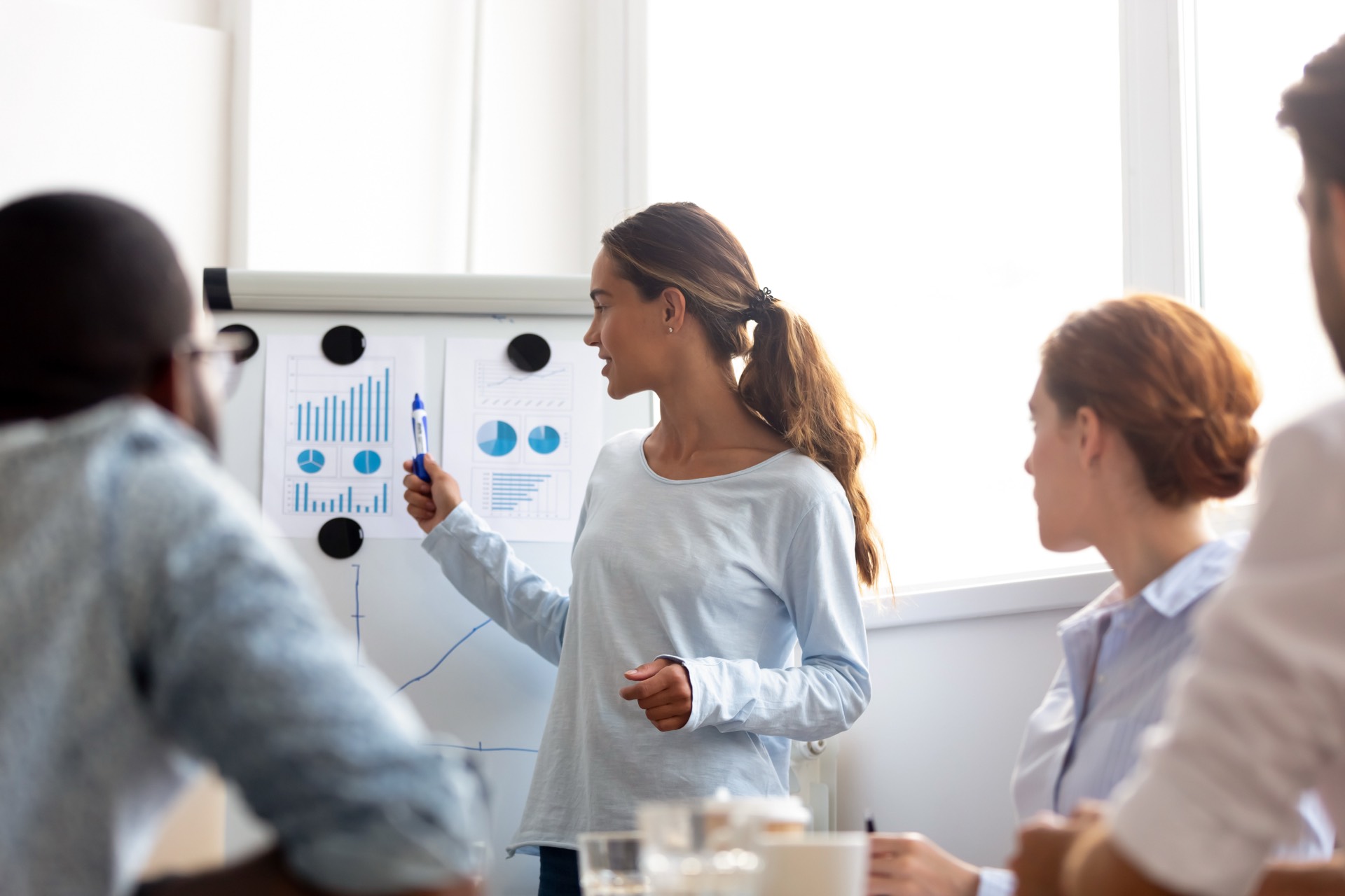 Woman presenting charts to colleagues in a bright meeting room