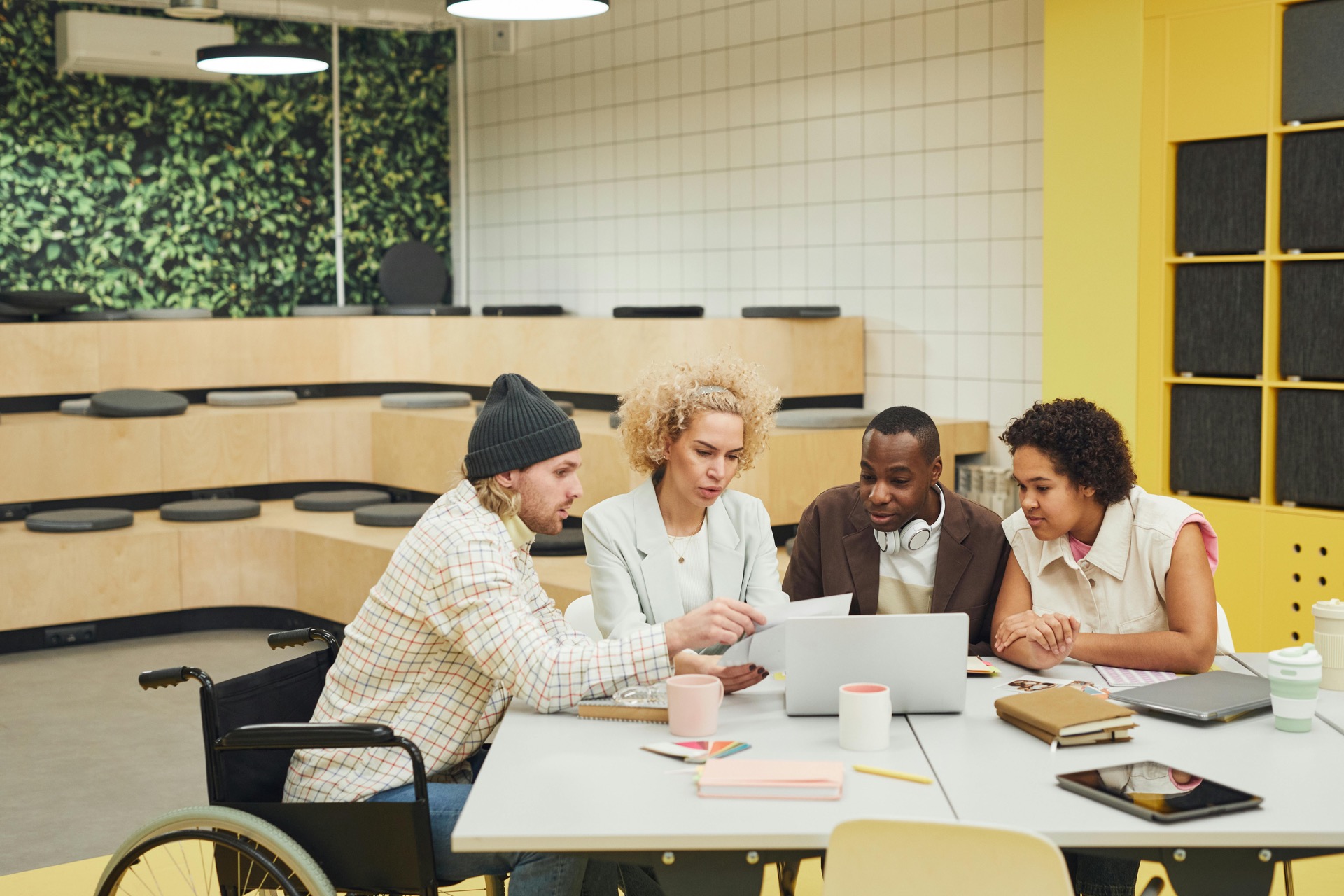 Four colleagues collaborating around a laptop at a meeting table